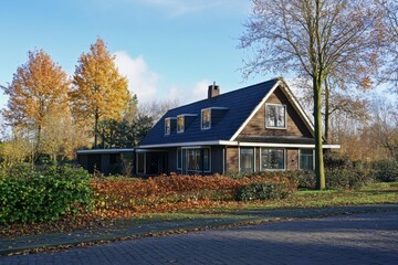 Fototapeta premium Nestled within a tranquil neighborhood, this delightful wooden house is beautifully framed by the vibrant colors of autumn foliage on a bright, sunny day