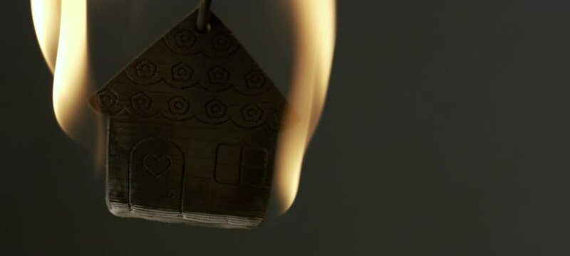 Extreme close-up view of a house model keychain made with wood burning in flames