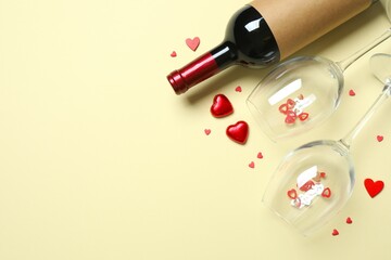 Bottle of red wine, glasses and hearts on a colored background