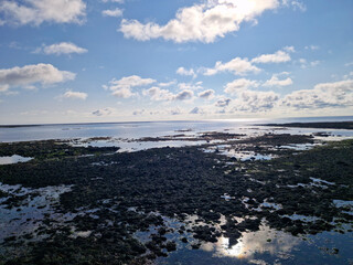 Close-up of a serene Icelandic shoreline featuring rocky textures, clear tidal pools, and a peaceful ocean under a vibrant sky