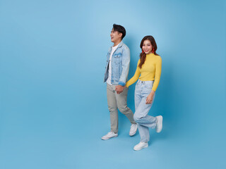 portrait of happy young Asian couple lover hold hands and walking together to copy space isolated on blue background.