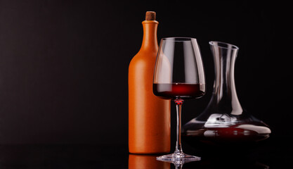 Elegant presentation of red wine in a glass, bottle and a decanter against a dark background