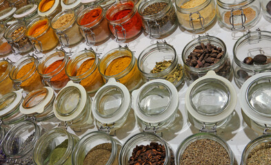 glass jars with flavorful and spicy spices from around the world for sale at the market stall