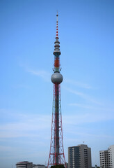 A view of a tall radio tower in an urban area, colorful, with white tones