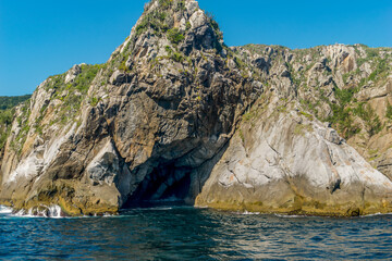Fototapeta premium Rocky mountain by the sea with a cave in the middle, located in the Cabo Frio region, Rio de Janeiro, Brazil.