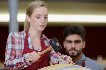 Fototapeta premium woman winery employee using a hammer in cellar