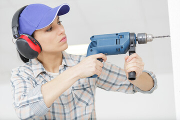 female carpenter at work using hand drilling machine