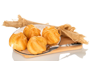 Several eclairs on a ceramic saucer on a wooden board isolated on a white background, close-up.