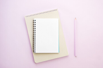 Notebooks and a pencil on lilac background
