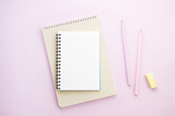 Notebooks, pencils and eraser on lilac background