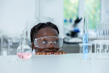 Scientist hiding behind table with petri dish and flask analyzing sample conducting research in...