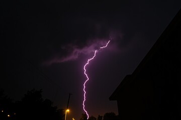Naklejka premium A lightning bolt illuminates the dark sky above a house, highlighting the drama and intensity of this moment