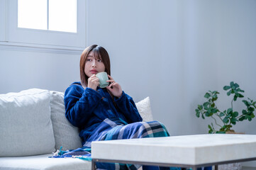 冬のリビングで飲み物を飲む日本人女性