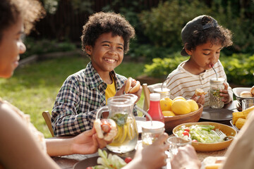 Smiling Boys Enjoying Outdoor Family Meal