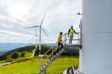 Engineer and operator working on a wind turbine platform, discussing maintenance and performance in...
