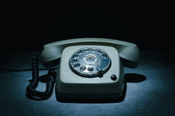 Vintage rotary telephone illuminated by soft light in a dark setting