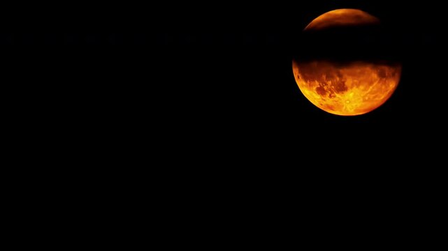 Time lapse of a dramatic yellow red moon passing, moving up, few clouds in the dark night background, copy space, darkness, only moon