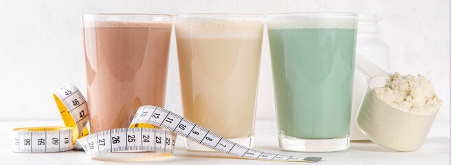 Assortment of different flavors of protein cocktails, with protein powder scoop, measuring tape. Protein shakes for weight loss, set every day protein goals, sport and fitness, healthy lifestyle