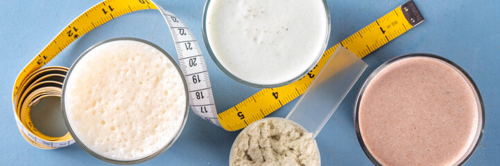 Assortment of different flavors of protein cocktails, with protein powder scoop, measuring tape. Protein shakes for weight loss, set every day protein goals, sport and fitness, healthy lifestyle