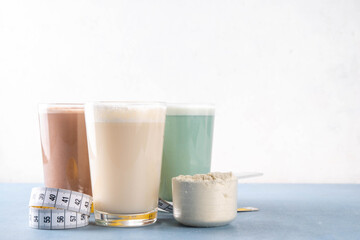 Assortment of different flavors of protein cocktails, with protein powder scoop, measuring tape. Protein shakes for weight loss, set every day protein goals, sport and fitness, healthy lifestyle