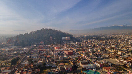 Aerial photography of the Nevado de Toluca landscape at dawn, with snow, clouds and a sky with ochre and red colors can be seen, in addition to a view of the magical town of Metepec.