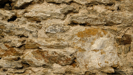 Texture of beige stone wall with rough masonry and uneven surface. Smooth, cracked surface. Old castle wall of stone different shape. Pattern with neutral colors. Minimal, stylish, trend concept.