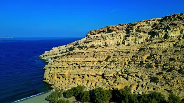Matala caves, sandy cliffs, turquoise sea, and a calm greek coastline, aerial view