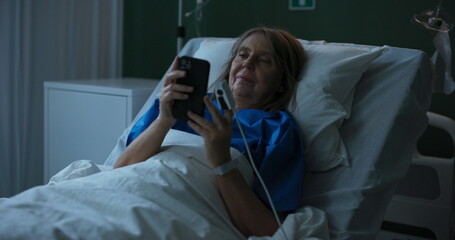 Obraz premium Photo shows elderly lady in hospital, looking at old photos on her phone.