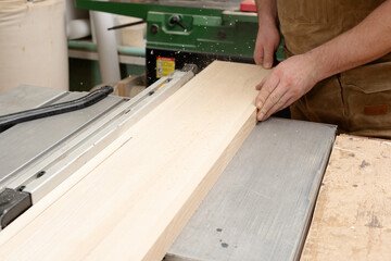 The carpenter saws the board, holding it with his hands