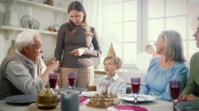 Family birthday party at home, happy childhood and parenthood, three generations . Grandparents, parents and little child sitting at table on cozy kitchen, happy people dinner together, family weekend - Powered by Adobe