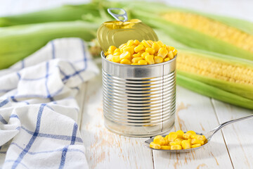 Canned young corn grain on a light kitchen table, selective focus.
