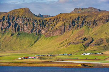 Majestic Icelandic mountains overlook quaint buildings nestled in lush green landscape
