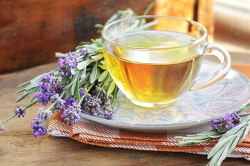 Lavender herbal tea in a glass cup with flowers on wooden rustic background, closeup, sleep and skin healing drink, natural medicine and naturopathy concept