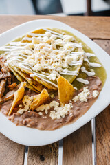Plato de chilaquiles verdes con frijoles refritos