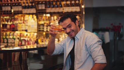 Smiling smart man drinking cocktail in Old fashioned with enjoy dancing in cheers with friends or stranger special vibrant beverage at nightclub on Friday meeting at luxurious counter bar. Vinosity.