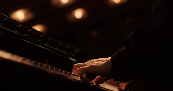 A close-up view of a pianist&rsquo;s hands gracefully playing the keys of a grand piano. The warm lighting emphasizes the precision and artistry of the performance