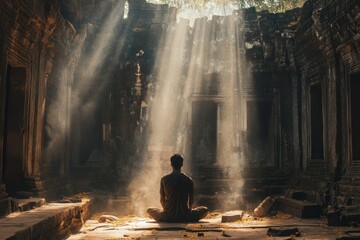 Obraz premium Monk meditating in ancient temple ruins with sunbeams illuminating dust particles