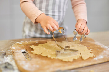cute hands of child cutting gingerbread cookies with a cookie cutter in kitchen. festive gingerbread cookies
