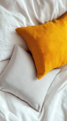 two decorative pillows on white bed linens with warm mustard and soft grey tones creating cozy mood copyspace concept of home decor and textile design