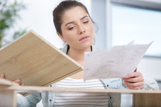 young lady reading instructions to assemble flatpack furniture