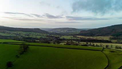 Obraz premium Stunning aerial view of green valley with fields and hills at sunset in the English countryside