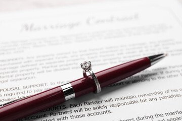 Fototapeta premium Marriage contract, pen and stylish ring on marriage contract, closeup