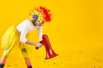 Girl dressed like clown with megaphone and confetti on yellow background, space for text. Surprise...