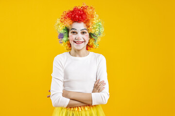 Happy girl dressed like clown on yellow background. Surprise party