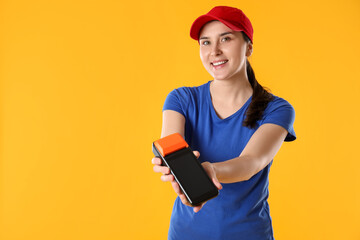 Happy courier with payment terminal on yellow background, space for text