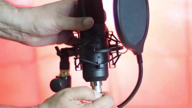 The technician is trying to connect the microphone. A person cannot plug in the cord into a socket.