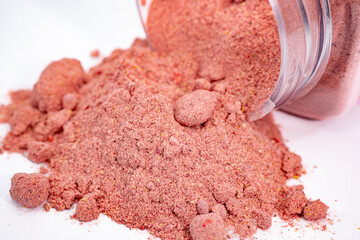 A close-up of freeze-dried crushed banana, strawberry, and raspberry powder spilling from a transparent container. A vibrant blend perfect for smoothies, desserts, or snacks.