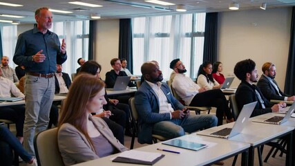 corporate training workshop with professionals in casual attire listening to speaker on stage