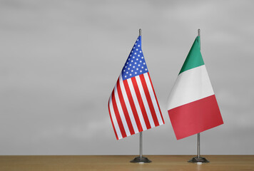 Tabletop flags of USA and Italy on a gray blurred background