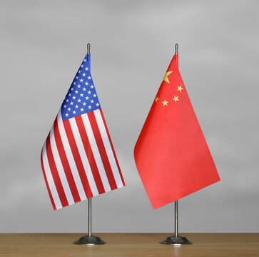 Tabletop flags of USA and China on a gray blurred background